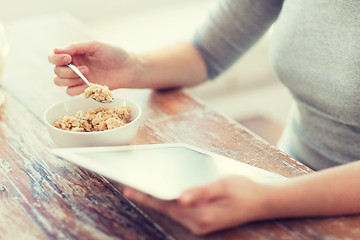 Image showing woman eating porridge and using tablet pc