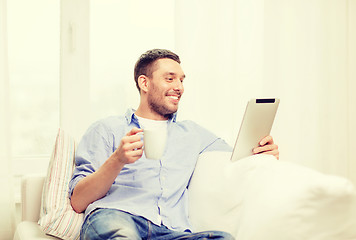 Image showing smiling man working with tablet pc at home