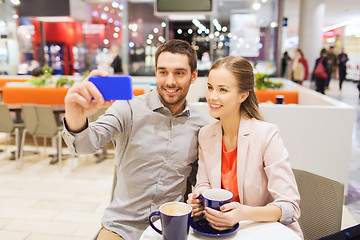 Image showing happy couple with smartphone taking selfie in mall