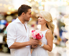 Image showing happy couple with flowers over lights background