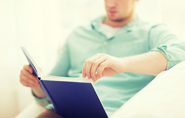 Image showing close up of man reading book at home