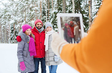 Image showing smiling friends with tablet pc in winter forest