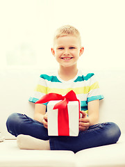 Image showing smiling little holding gift box sitting on couch