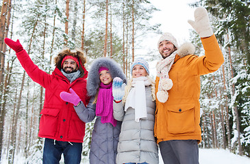 Image showing group of friends waving hands in winter forest