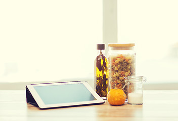 Image showing close up of tablet pc olive oil, pasta and pumpkin