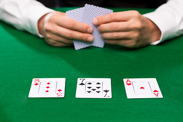 Image showing poker player holding playing cards at casino table