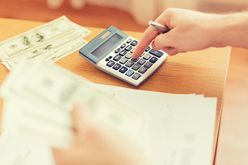 Image showing close up of man counting money and making notes