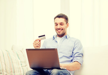 Image showing smiling man working with laptop and credit card