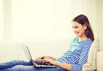 Image showing smiling teenage girl with laptop computer at home