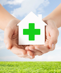 Image showing hands holding paper house with green cross