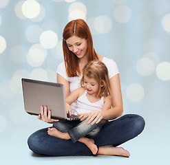 Image showing happy mother with adorable little girl and laptop