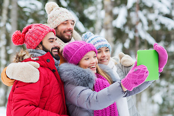 Image showing smiling friends with tablet pc in winter forest