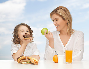 Image showing happy mother and daughter eating breakfast