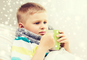 Image showing ill boy with flu in bed drinking from cup at home