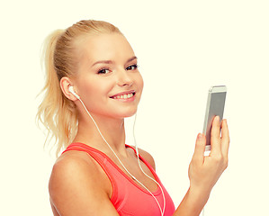 Image showing smiling sporty woman with smartphone and earphones