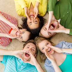 Image showing smiling people lying down on floor and screaming