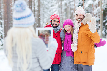 Image showing smiling friends with tablet pc in winter forest