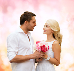 Image showing happy couple with flowers over lights background