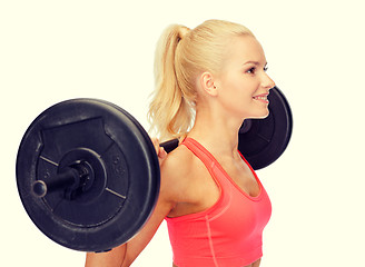 Image showing smiling sporty woman exercising with barbell