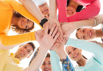 Image showing smiling teenagers with hands on top of each other