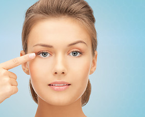 Image showing beautiful young woman pointing finger to her eye