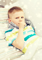 Image showing ill boy with scarf lying in bed and coughing