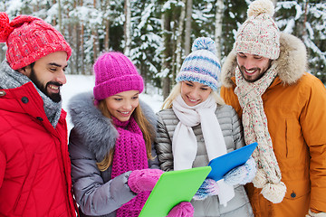 Image showing smiling friends with tablet pc in winter forest