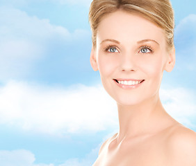 Image showing close up of smiling woman over blue sky background