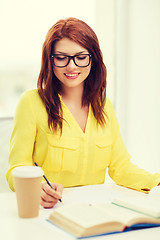 Image showing smiling student girl reading books in library