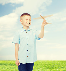 Image showing smiling little boy holding a wooden airplane model