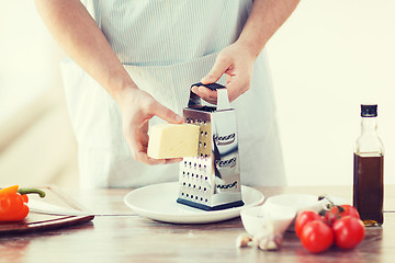 Image showing close up of male hands grating cheese