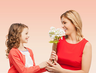 Image showing happy little daughter giving flowers to her mother