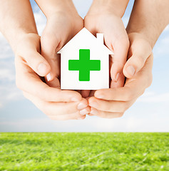 Image showing hands holding paper house with green cross