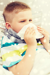 Image showing ill boy blowing nose with tissue at home