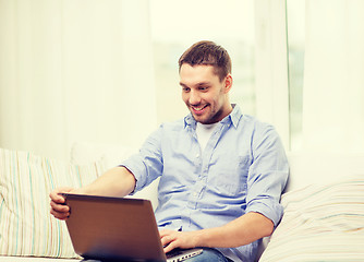 Image showing smiling man working with laptop at home