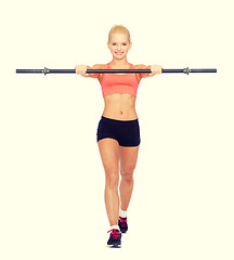 Image showing smiling sporty woman exercising with barbell