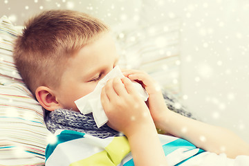 Image showing ill boy blowing nose with tissue at home