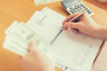 Image showing close up of man counting money and making notes