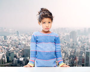 Image showing sad little girl over city background