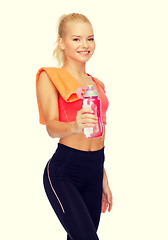 Image showing smiling sporty woman with water bottle and towel