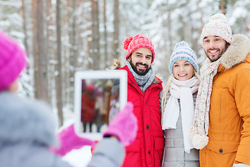 Image showing smiling friends with tablet pc in winter forest