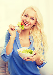 Image showing smiling young woman with green salad at home