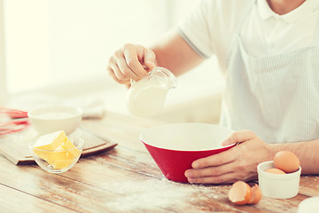 Image showing close up of male hand pouring milk in bowl