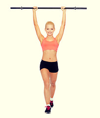 Image showing smiling sporty woman exercising with barbell