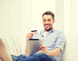 Image showing smiling man working with tablet pc at home