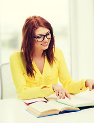 Image showing smiling student girl reading books in college