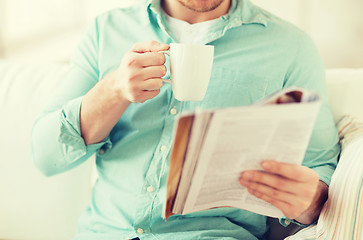 Image showing close up of man with magazine drinking from cup