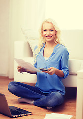 Image showing smiling woman with papers, laptop and calculator