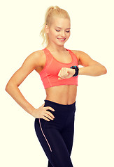 Image showing smiling woman with heart rate monitor on hand