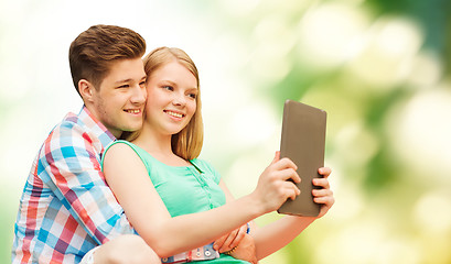 Image showing couple with tablet pc taking selfie over green